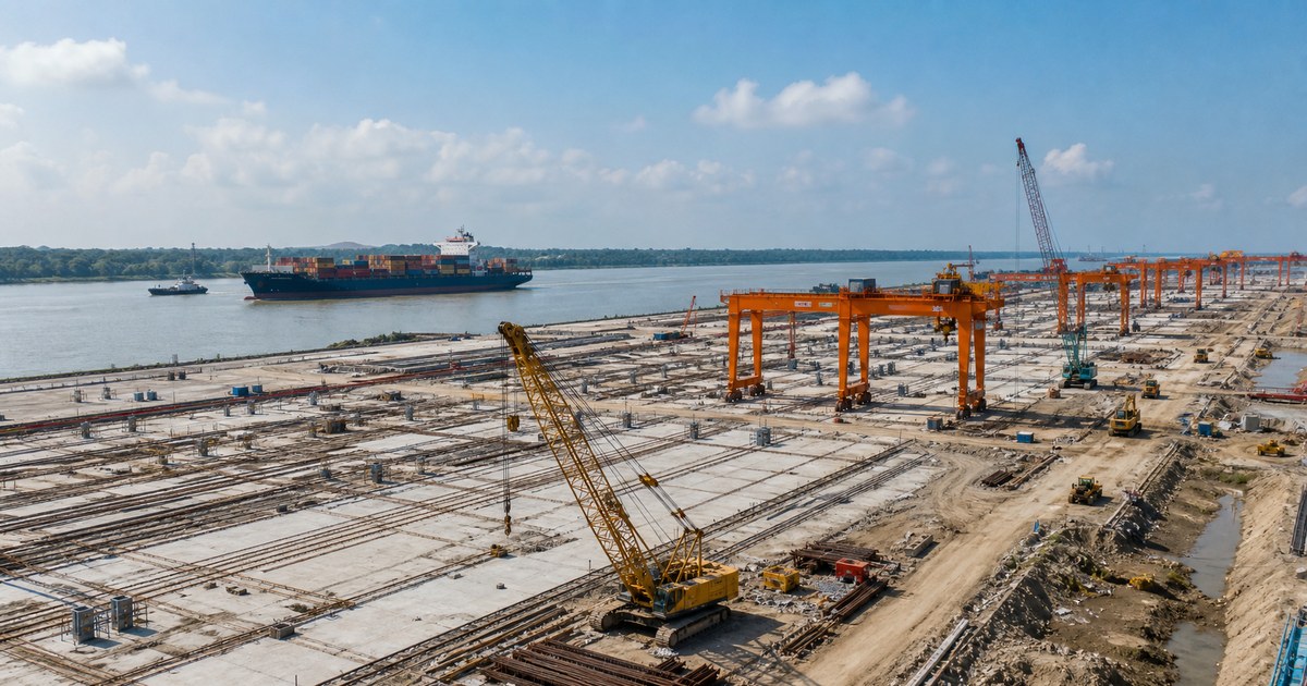 Terminal portuaria en construcción junto a un río con grúas y buque portacontenedores