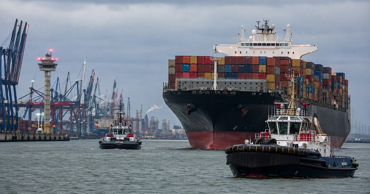 Remolcadores asistiendo a un portacontenedores en un puerto europeo con cielo nublado