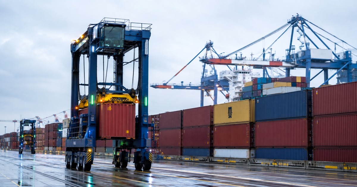 Straddle carrier moderno moviendo contenedores en una terminal portuaria organizada