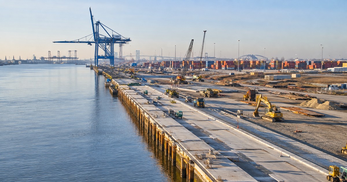 Terminal marítima en construcción con contenedores y grúas junto al río
