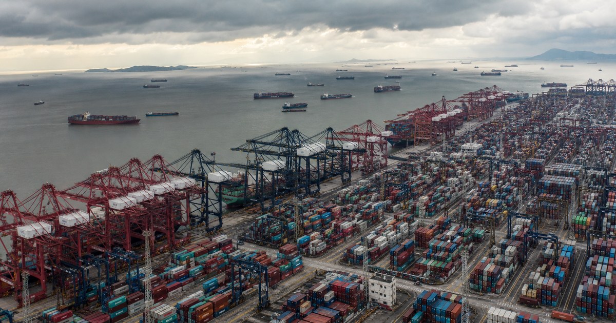 Puerto de contenedores congestionado con buques esperando en bahía bajo cielo nublado